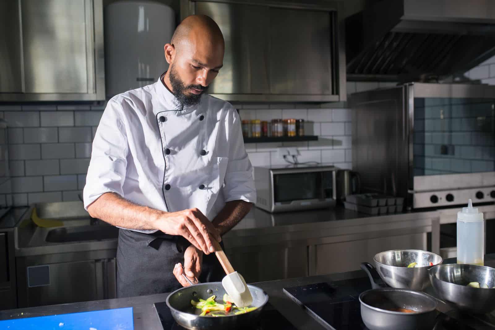 Cuisinier préparant des légumes à la poêle dans une cuisine professionnelle