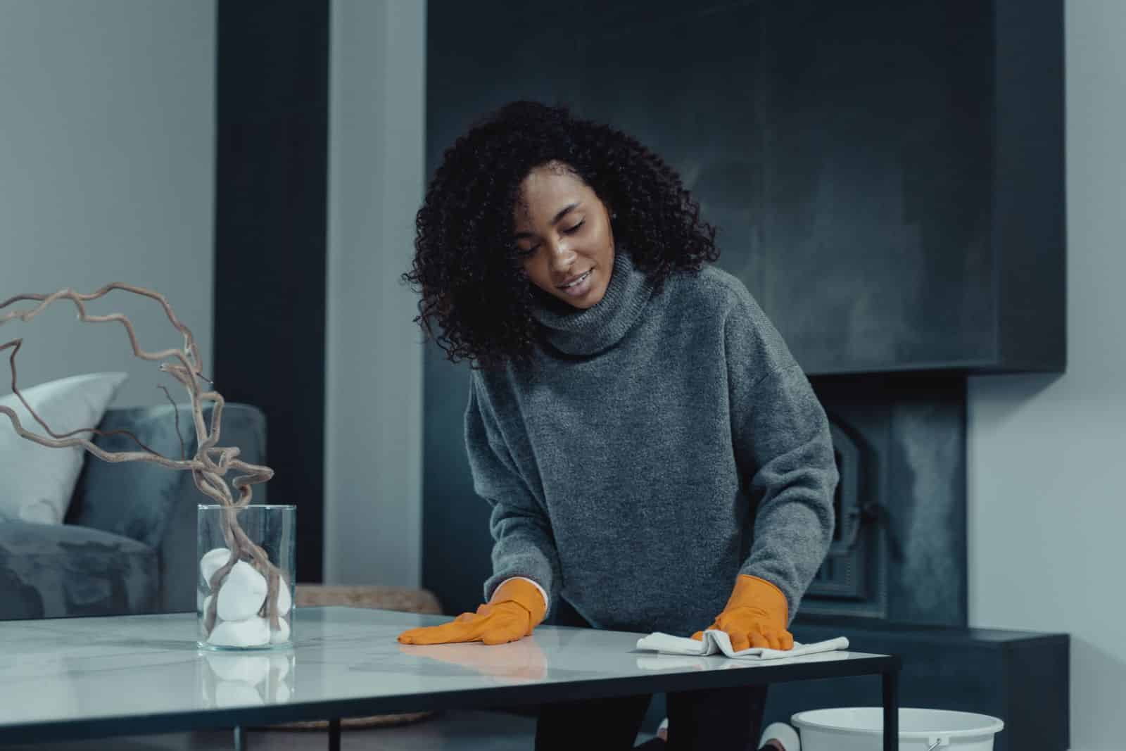 Agente d’entretien nettoyant une table avec des gants orange